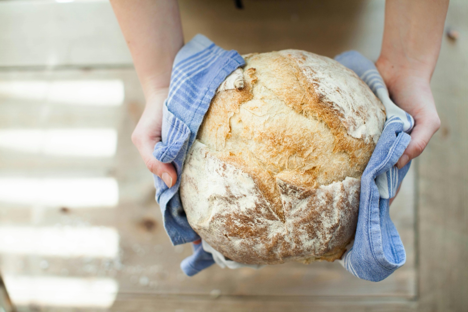 Hands holding a fresh sourdough loaf